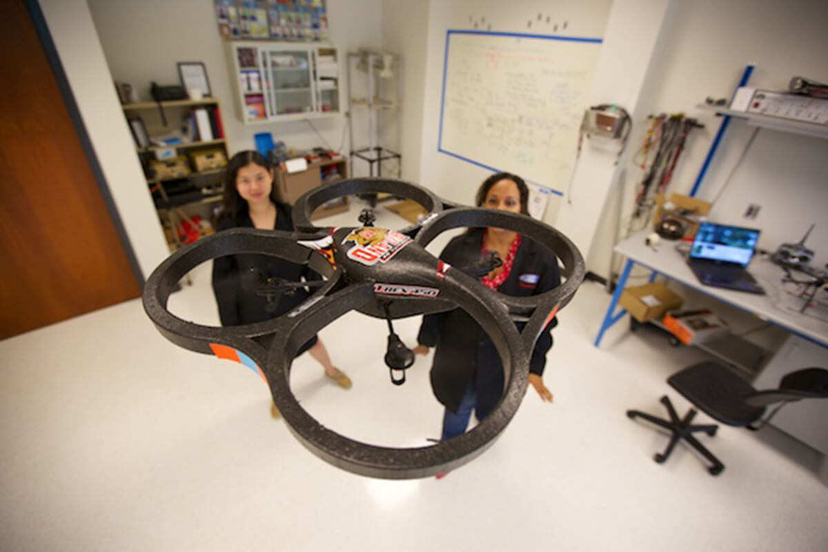 Female NIA researchers flying drone in lab