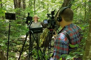 NIA's Seth Robinson records video of female ranger speaking in forest