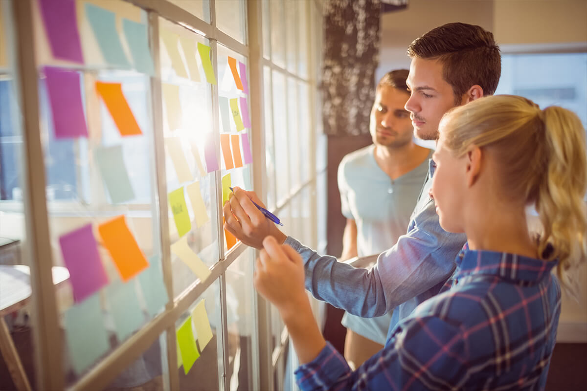 Three young professionals work together to brainstorm on sticky notes